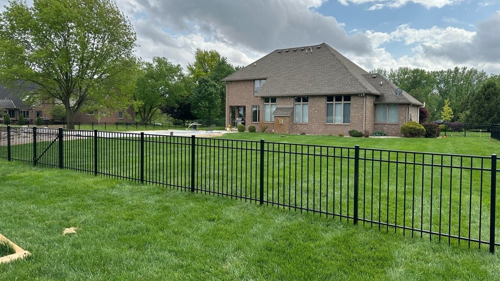 Black aluminum fence with a walk gate enclosing a backyard pool area in Sharpsville, IN