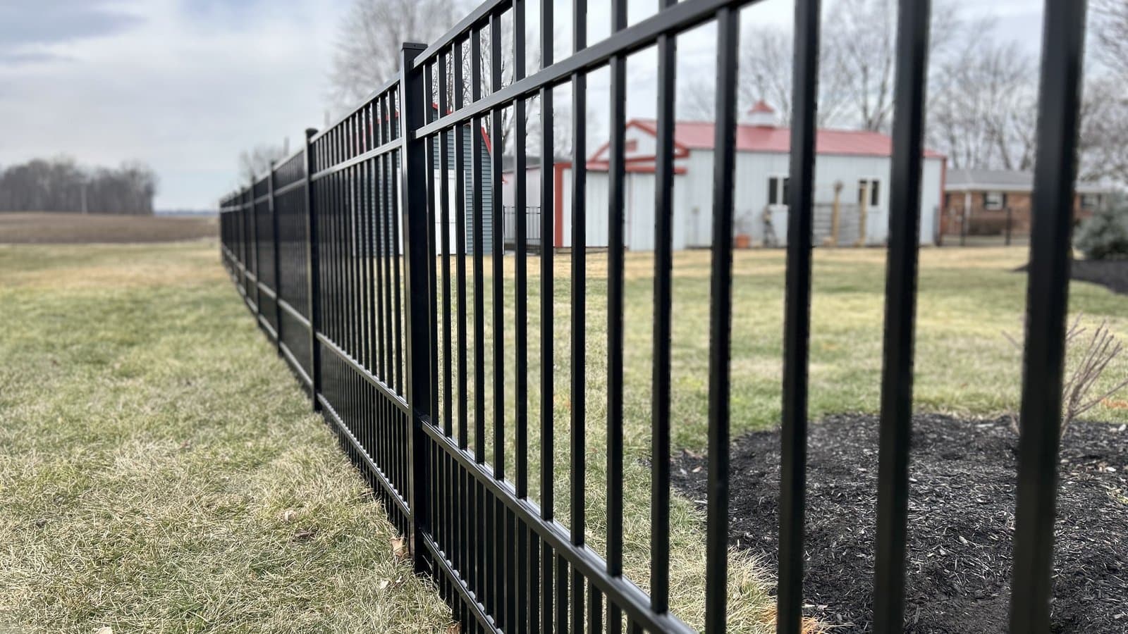 Black aluminum picket fence across a rural yard in Westfield, IN