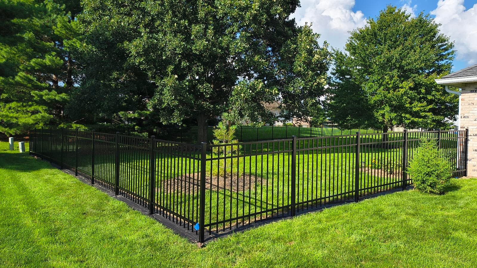 Black three-rail smooth-top aluminum fence beside a brick home, shown as a fence design example for Galveston, Indiana yards.