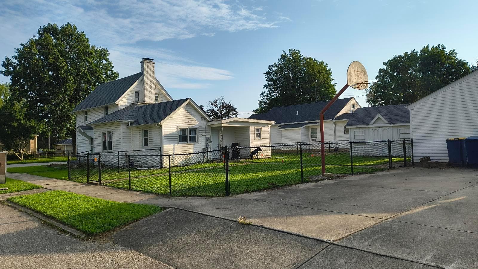 Black chain-link fence enclosing a corner yard beside a sidewalk and driveway, shown as a fence design example for Galveston, Indiana yards.