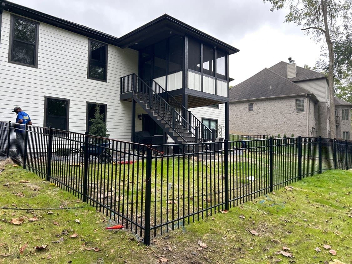 Black aluminum fencing frames the lawn behind a white home.
