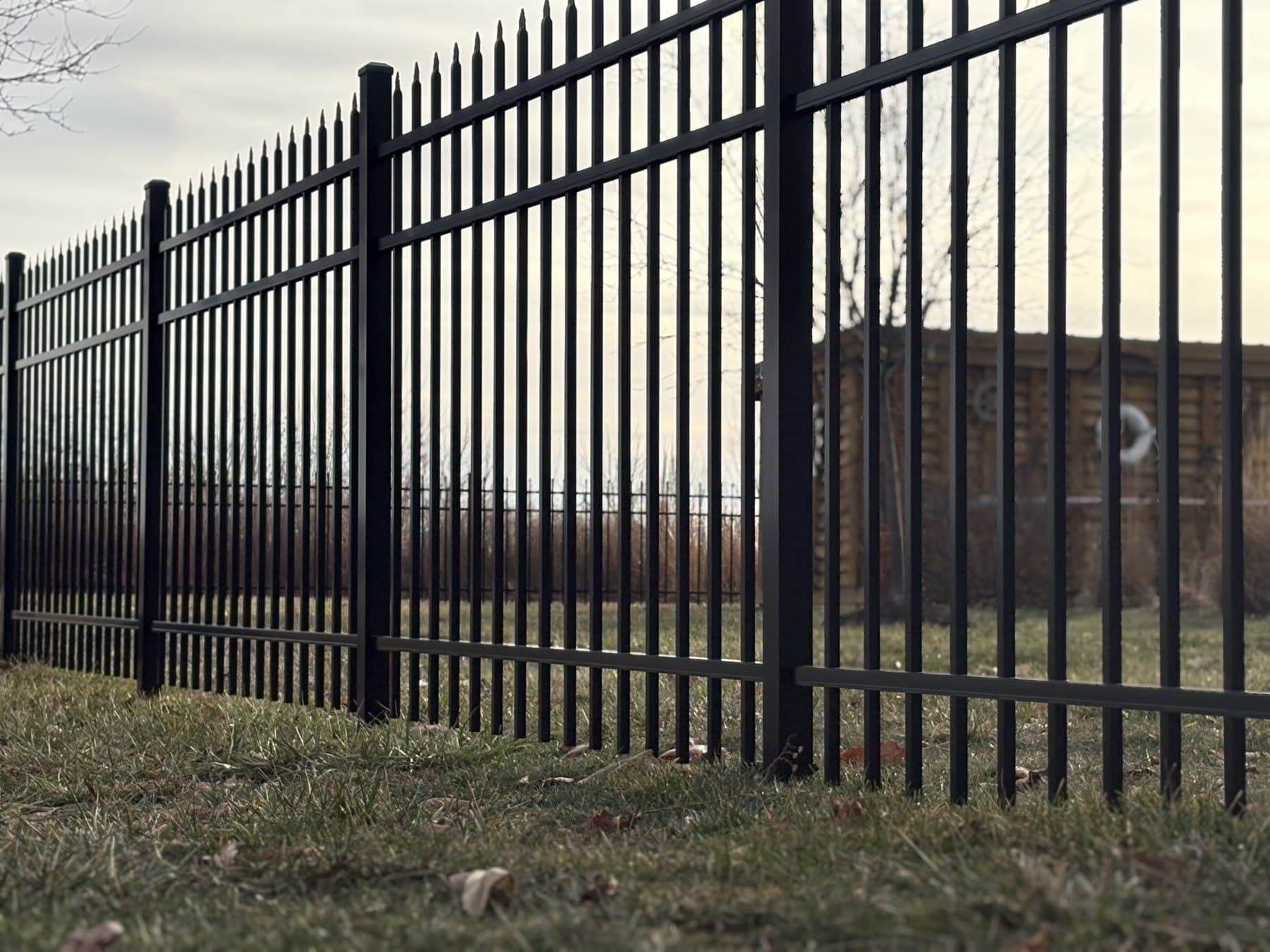 Tall black pickets form a narrow pattern beside the house.