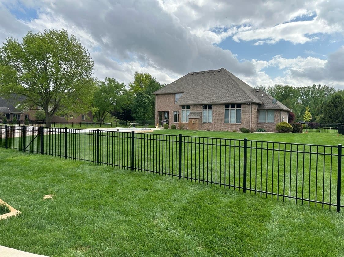 Black aluminum panels stretch across the yard with a home beyond.