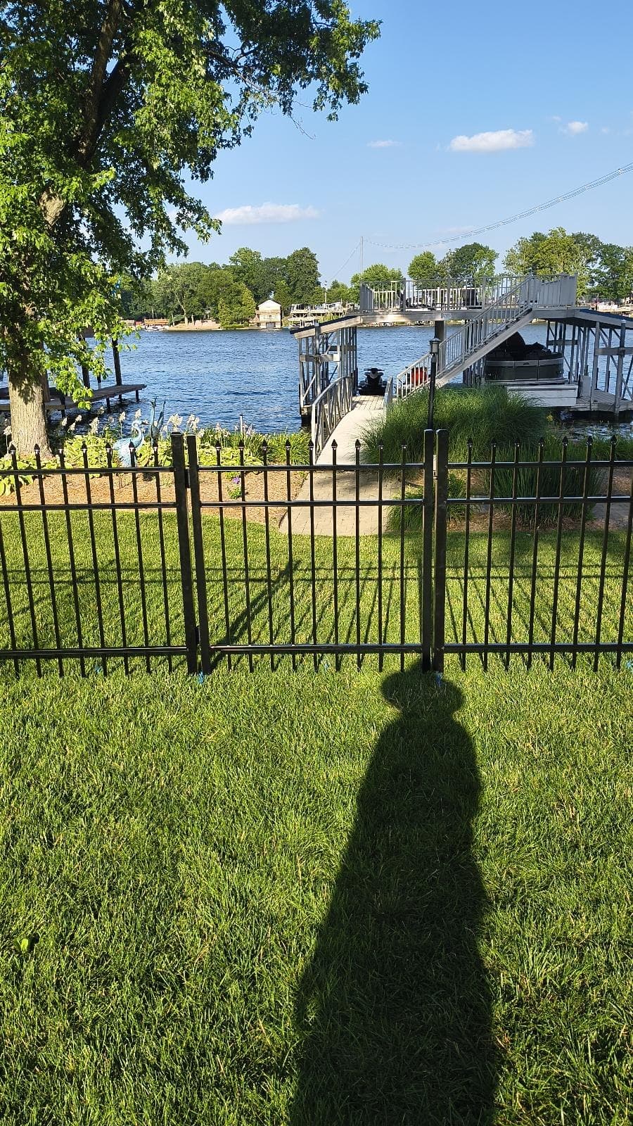 An aluminum gate connects the lawn with the space beyond the fence.