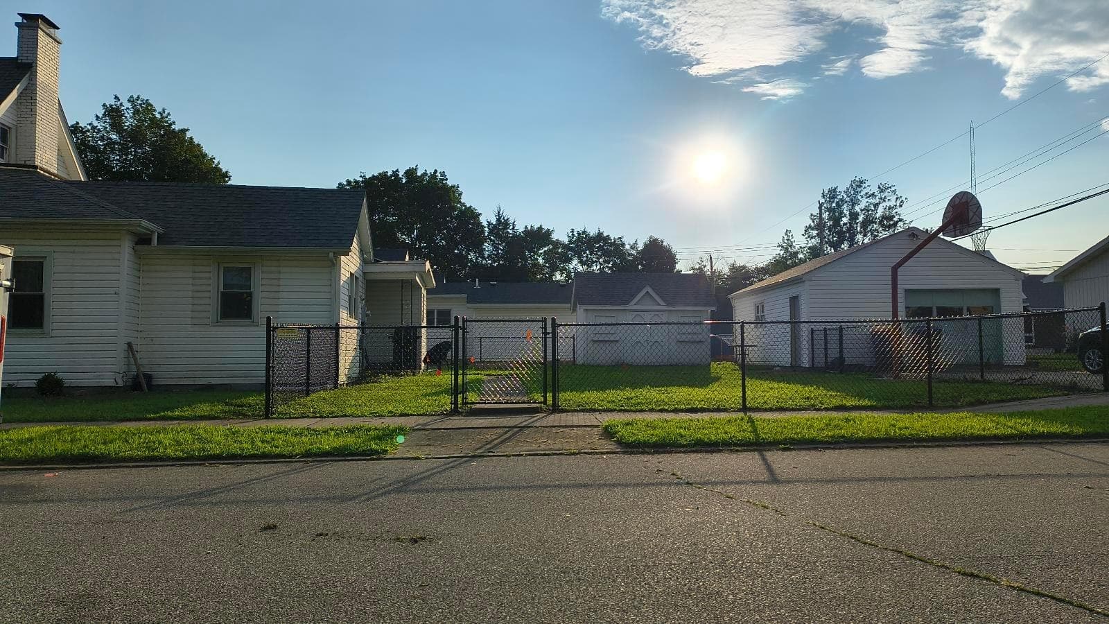 A chain-link gate faces the street between sections of yard fencing.