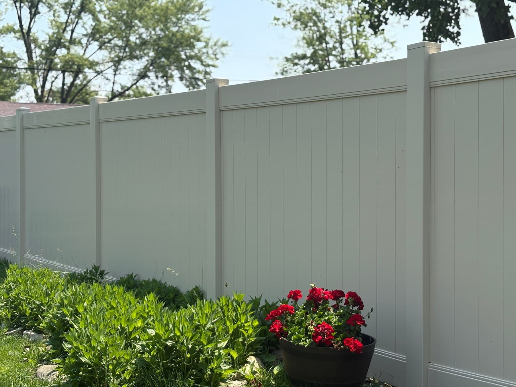 White vinyl privacy panels stand behind a colorful flower bed.