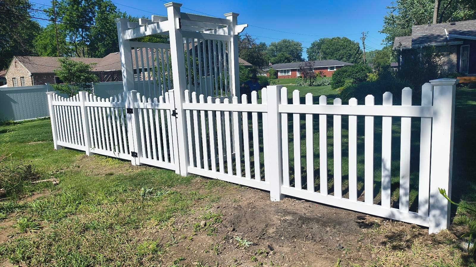 White picket fencing meets an arbor at the garden entrance.