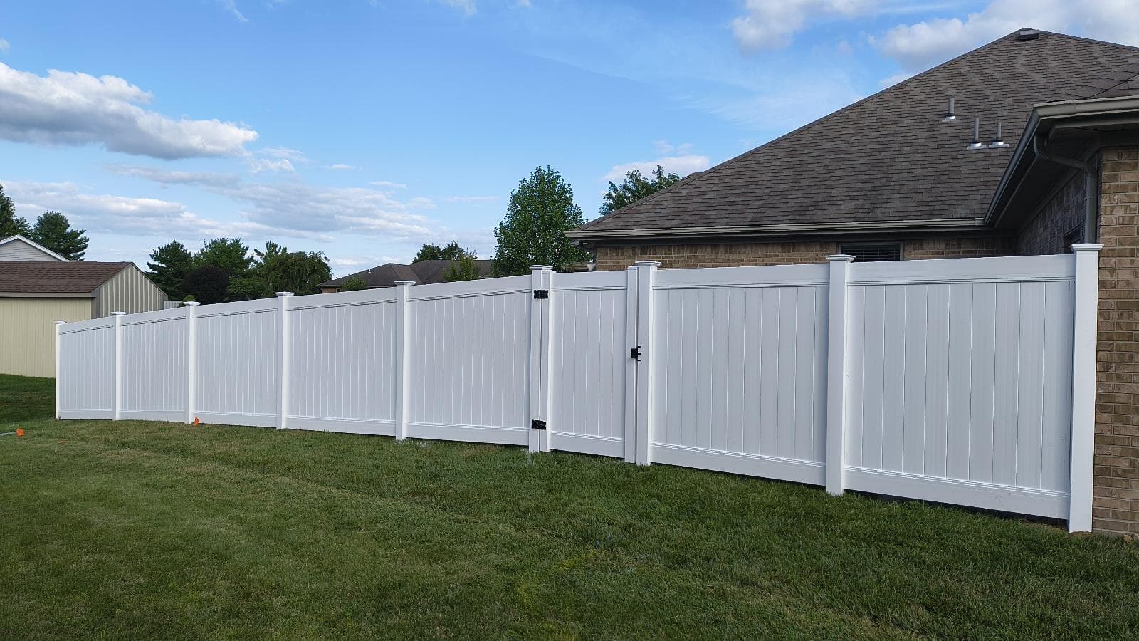 A white gate sits within a run of solid privacy panels.