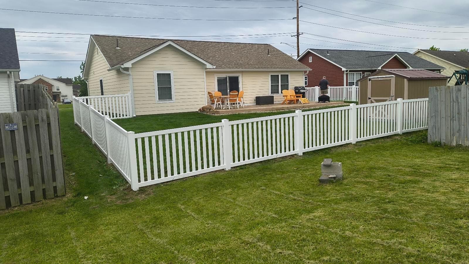 White picket fencing borders the lawn with nearby homes still visible.
