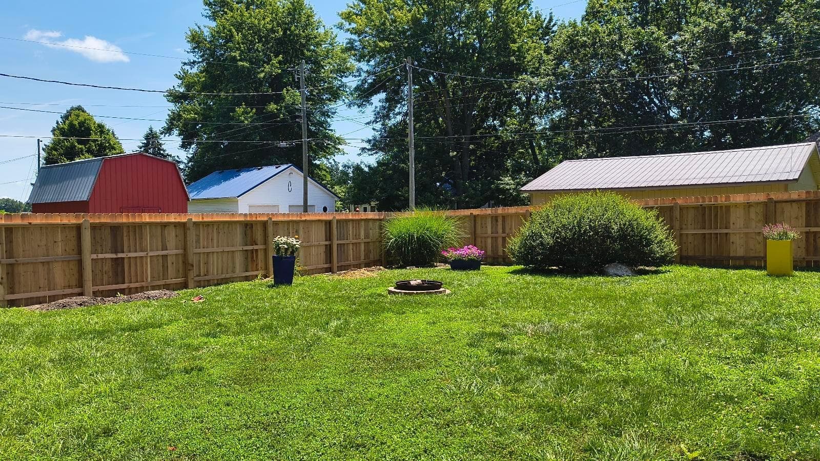 Wood privacy fencing surrounds an open lawn with garden features.