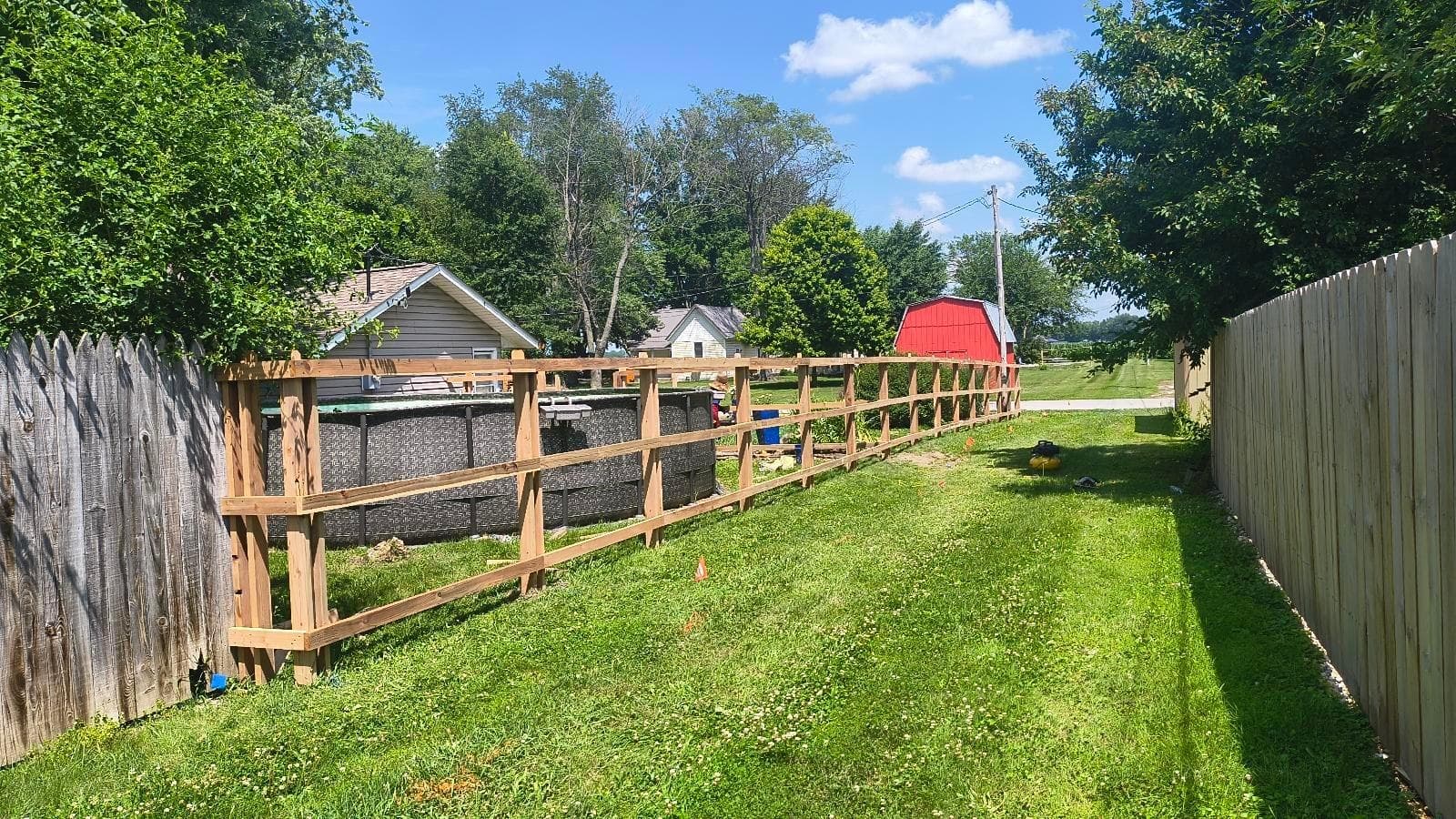 An installer works along a partially built wood fence frame.