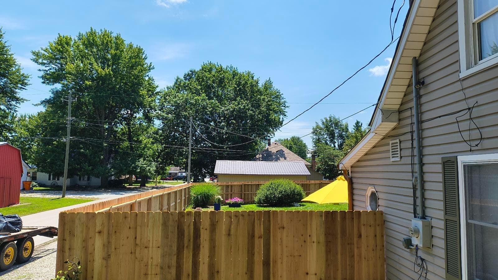 A wood fence follows the grass strip alongside a home.