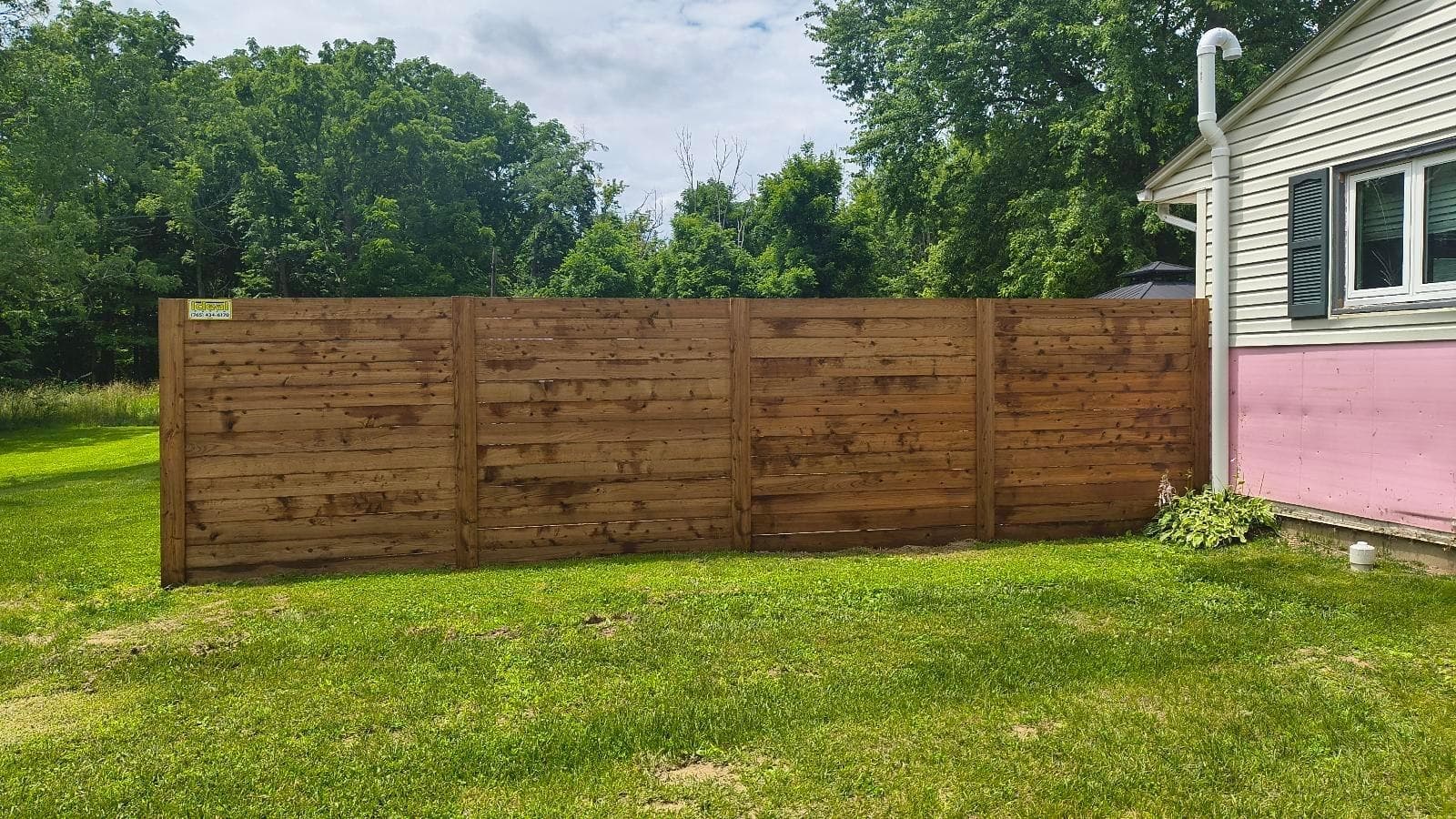 Horizontal wood boards create a privacy screen beside the lawn.