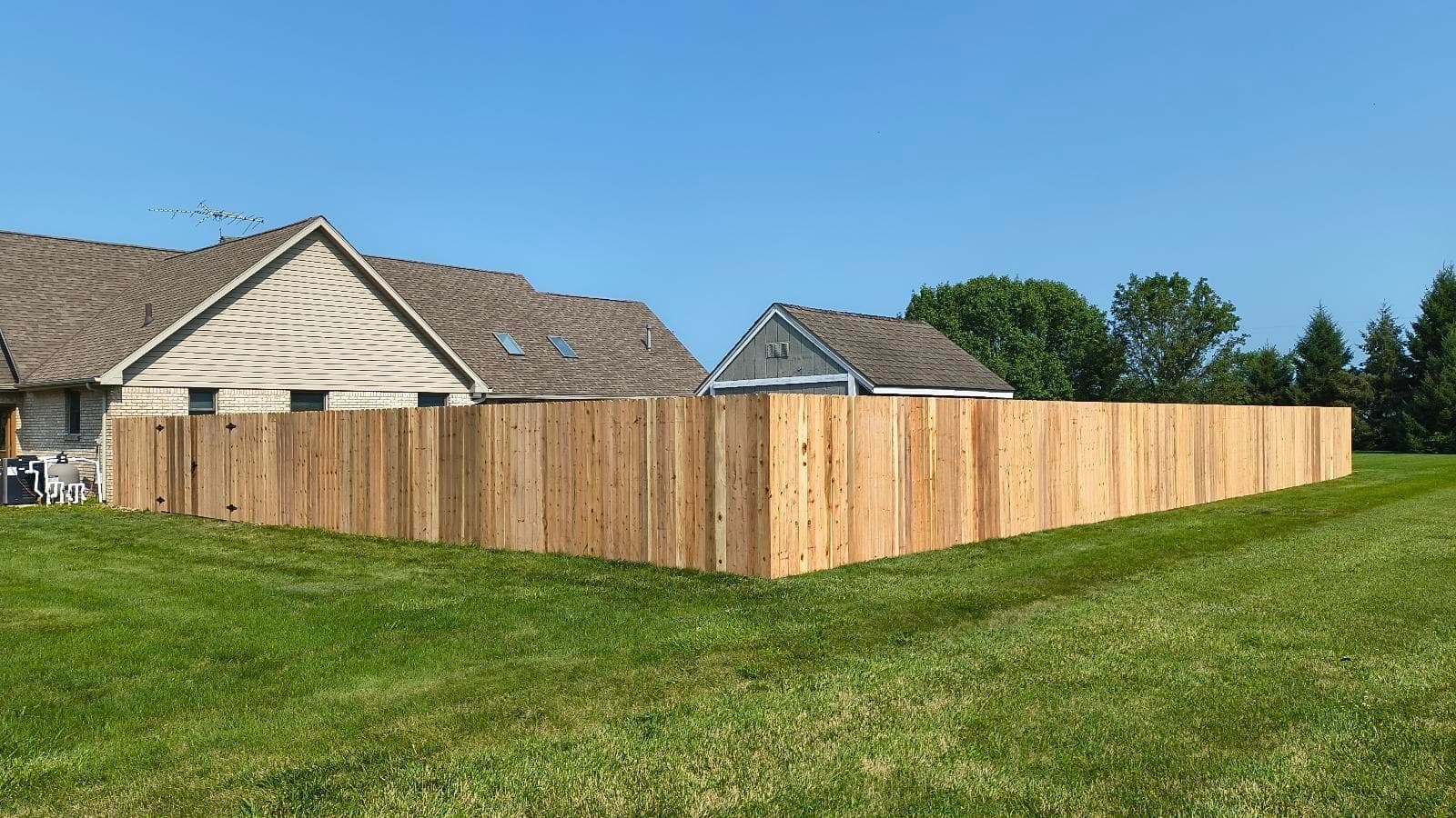 Wood privacy fencing encloses a broad, open lawn.