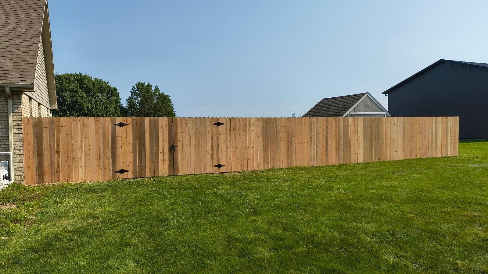 A long run of wood boards borders the lawn behind the homes.