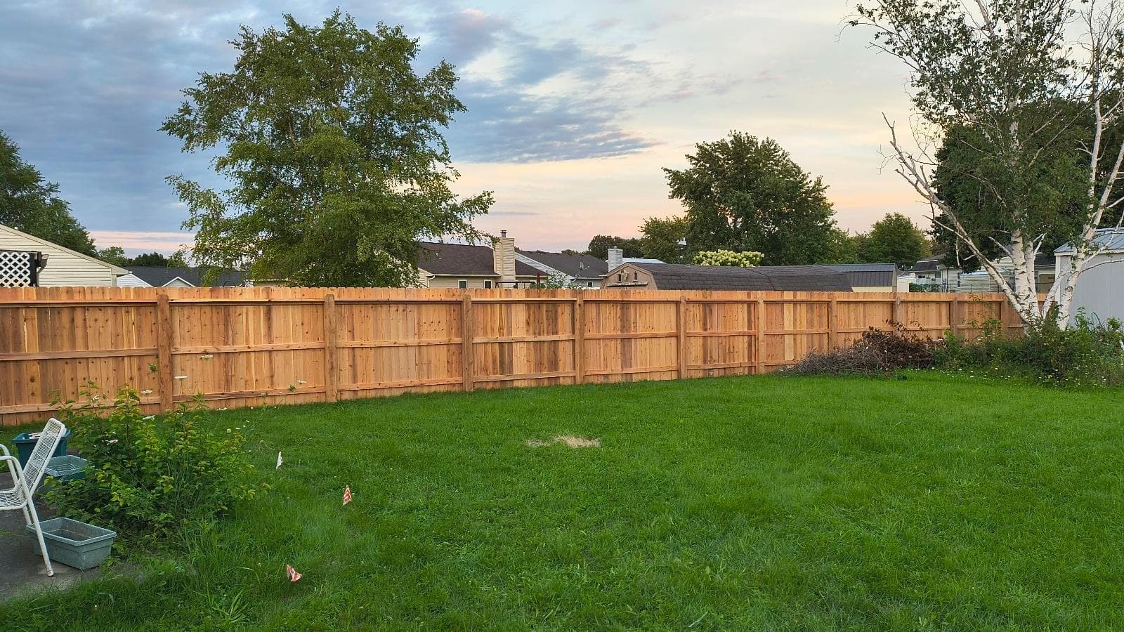 Posts and horizontal support rails line the inside of a wood fence.