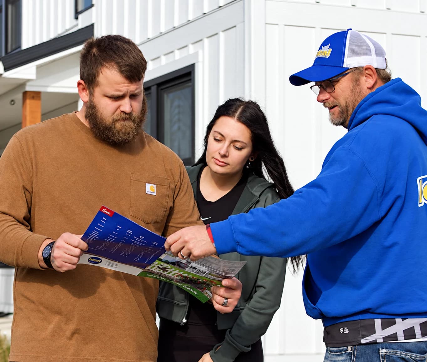 Ideal Fence representative reviewing fence styles in a brochure for vinyl fence with a couple beside white vinyl fencing.