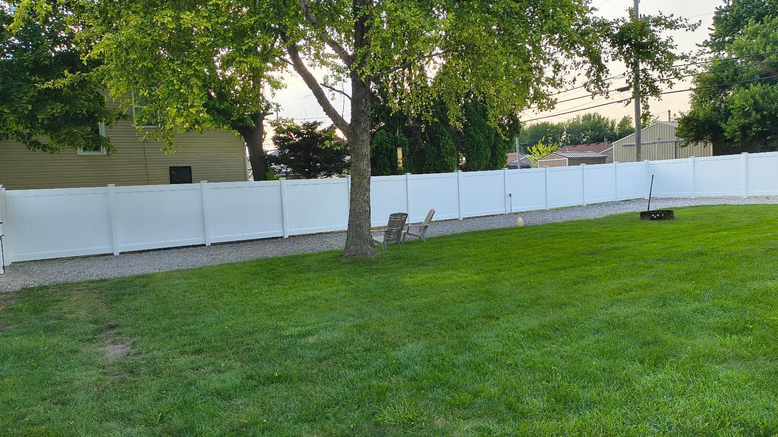 White vinyl privacy panels run along a grassy backyard.