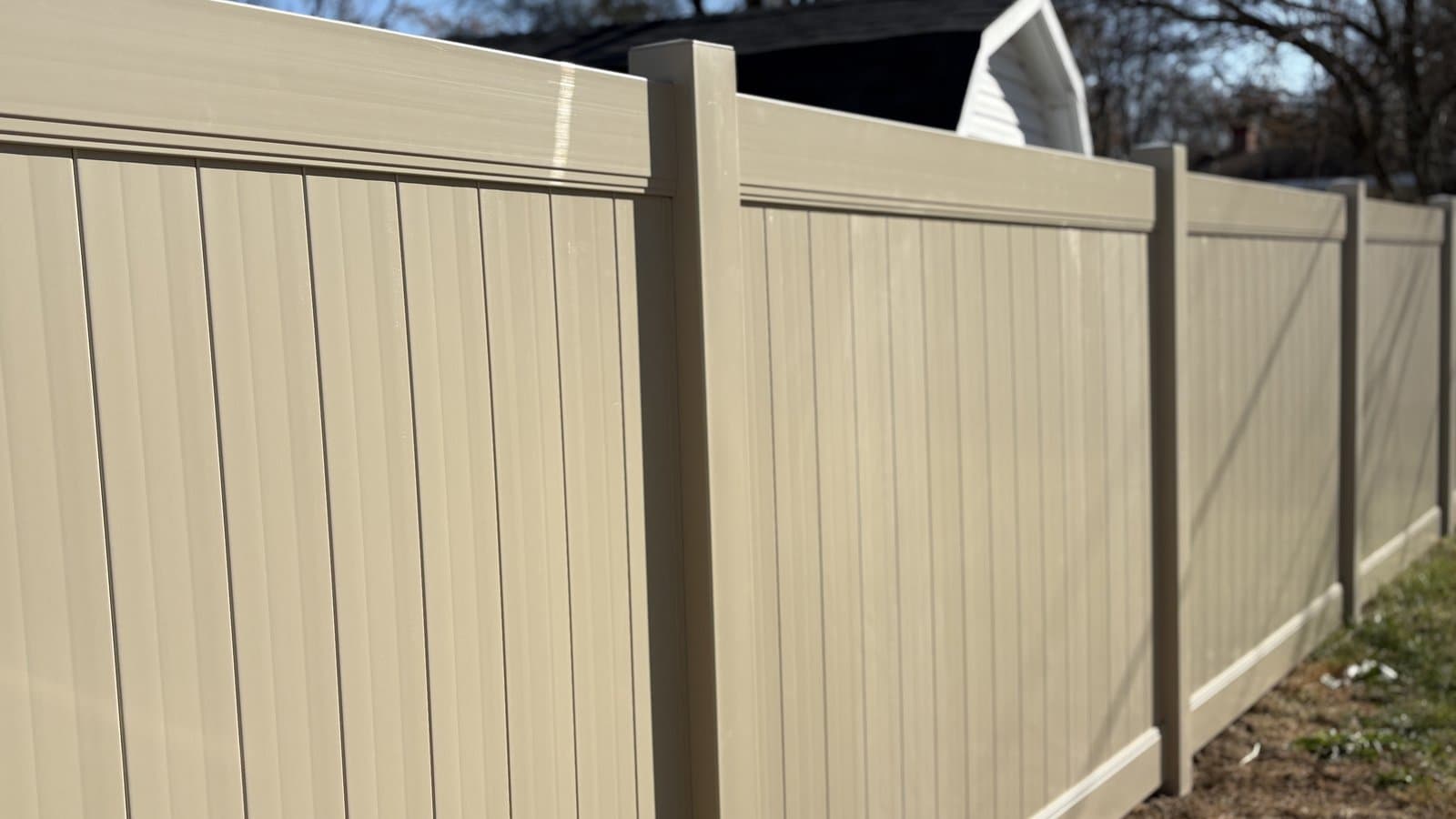 Tan vinyl privacy fence along a wooded backyard in Walton, IN