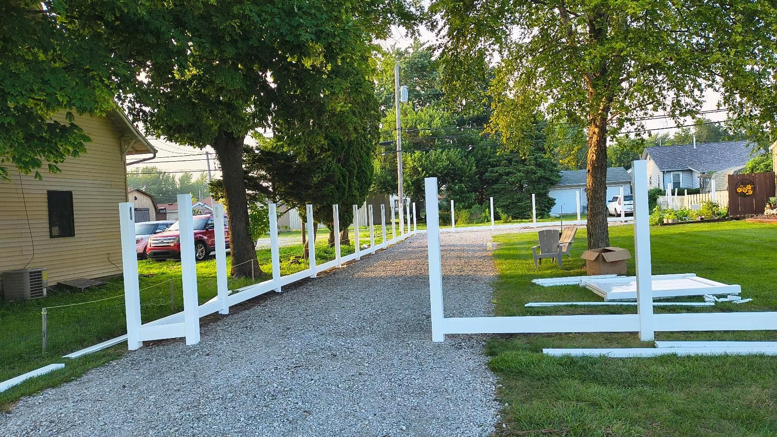 White vinyl sleeves over steel posts with bottom rails in place along a gravel driveway at the Kokomo installation.