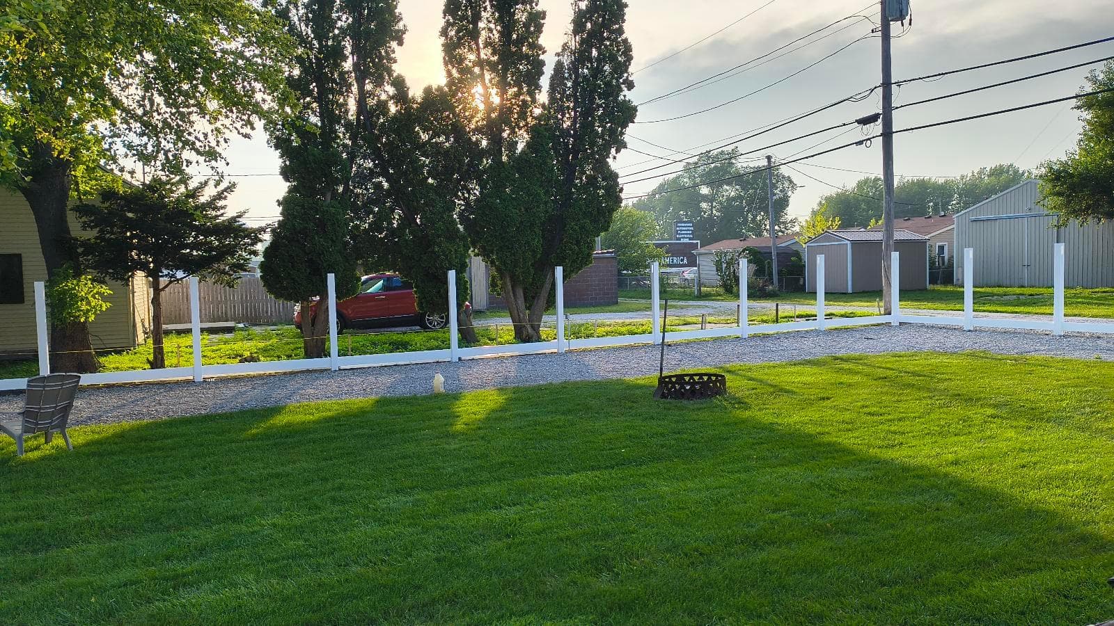 White vinyl post sleeves and bottom rails along a Kokomo fence line, viewed across the lawn before privacy panels are fitted.