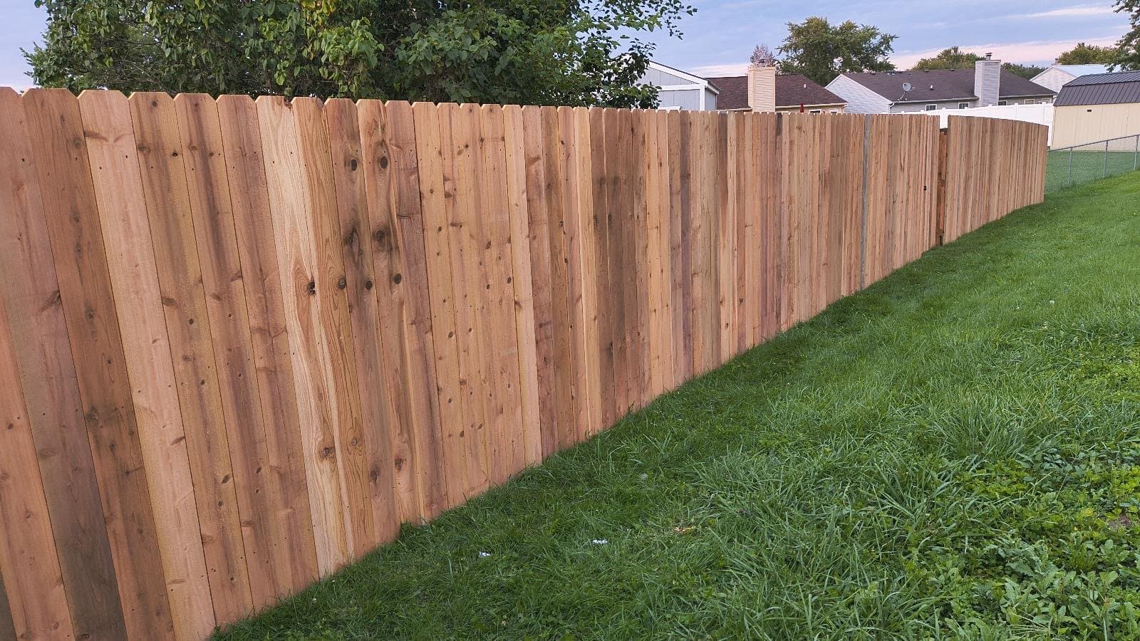 Wood dog-ear privacy fence along a green lawn in Galveston, IN